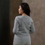 Kobieta w szarym golfie widziana od tyłu w jasnym wnętrzu
