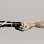 Zbliżenie ludzkiej wytatuowanej ręki przybijającej żółwika z protezą robota