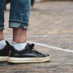 Czarne sneakersy do miasta zestawione z podwiniętymi dżinsami