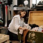 Młoda kobieta przegląda eleganckie ubrania w sklepie z odzieżą używaną