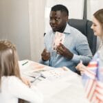 Nauczycielka tłumaczy uczniom angielski, trzymając kartę z flagą brytyjską