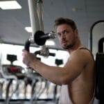 Skupiony mężczyzna ćwiczy biceps na siłowni