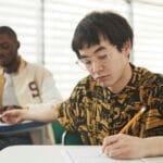 Studenci piszą egzamin przy ławkach w sali podczas rekrutacji na AWF