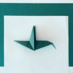 Turkusowy ptak z origami na białym i turkusowym tle