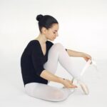 Baletnica wiążąca pointy podczas ćwiczeń w studiu