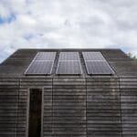 Drewniany dom na Mazurach z panelami fotowoltaicznymi pod chmurami