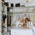 Dwie eleganckie kobiety stoją przy uporządkowanej, luksusowej szafie
