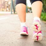 Kobieta idąca ścieżką w różowych sneakersach podczas miejskiego spaceru