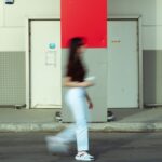Kobieta idąca ulicą obok czerwonej kolumny w miejskiej scenerii