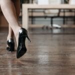 Kobieta w eleganckich szpilkach idzie po biurowej drewnianej podłodze