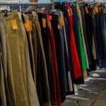 Kolorowe spodnie różnych fasonów na stoisku z odzieżą używaną