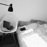 Mały sypialniany kącik do pracy z laptopem na krześle w świetle słońca