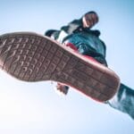 Podeszwa sneakersa widziana z dołu na tle błękitnego nieba