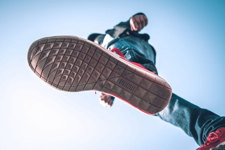 Podeszwa sneakersa widziana z dołu na tle błękitnego nieba